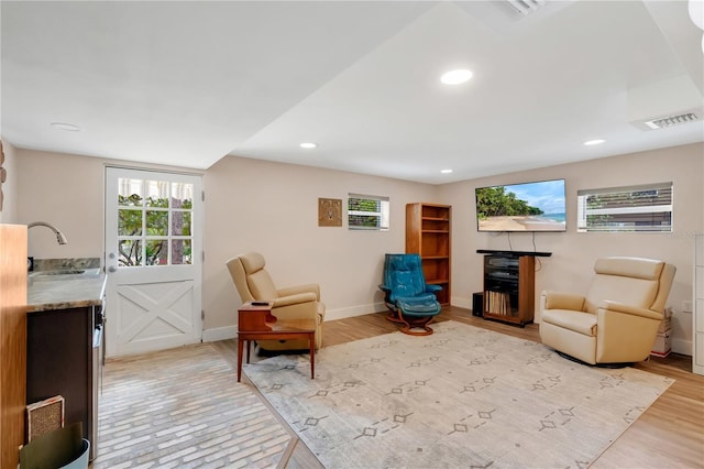 living area with light wood-style flooring, recessed lighting, visible vents, and baseboards