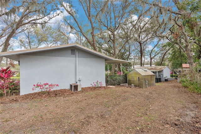 view of side of property with an outbuilding, stucco siding, an exterior structure, and central air condition unit