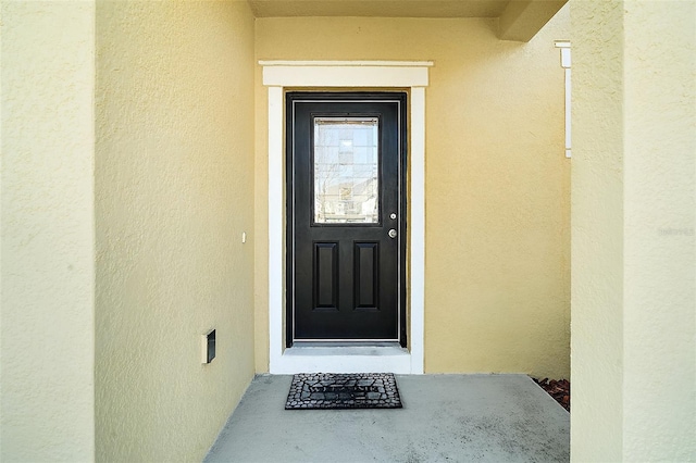 doorway to property featuring stucco siding