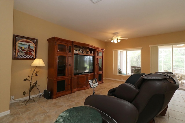 living room with ceiling fan, baseboards, and light tile patterned flooring