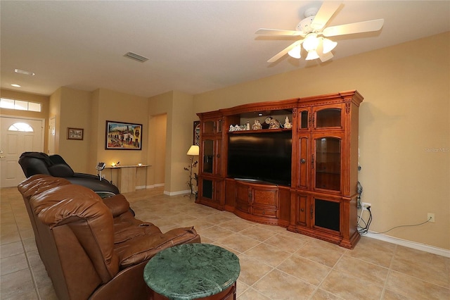 living area featuring light tile patterned floors, a ceiling fan, visible vents, and baseboards