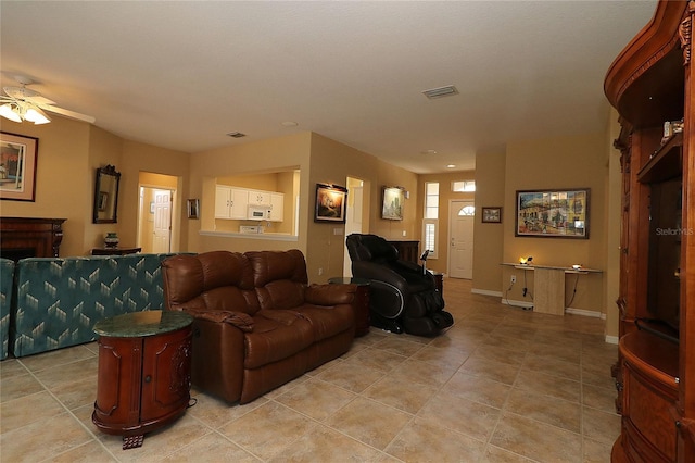 living room featuring a fireplace, visible vents, a ceiling fan, light tile patterned flooring, and baseboards