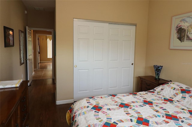 bedroom featuring a closet, visible vents, baseboards, and wood finished floors