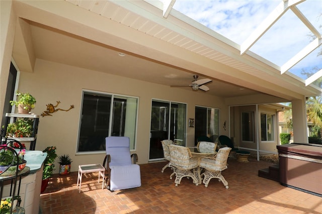 view of patio / terrace with glass enclosure, a hot tub, and a ceiling fan