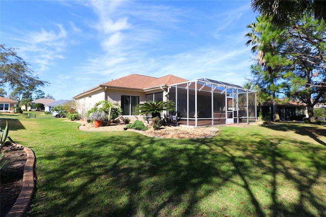 back of property featuring a yard, a lanai, and stucco siding