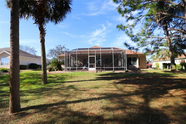 rear view of property featuring a lawn and a lanai