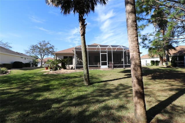 rear view of house with glass enclosure and a lawn