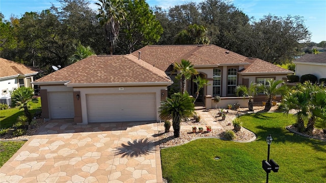 view of front of home featuring roof with shingles, stucco siding, an attached garage, a front yard, and driveway