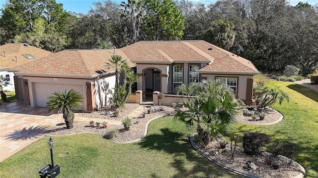 single story home with a shingled roof, a front yard, an attached garage, and stucco siding