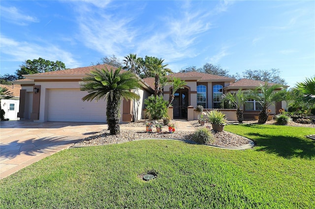 view of front of house with driveway, a garage, a front lawn, and stucco siding