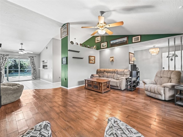 living area with vaulted ceiling, a textured ceiling, wood finished floors, baseboards, and ceiling fan with notable chandelier