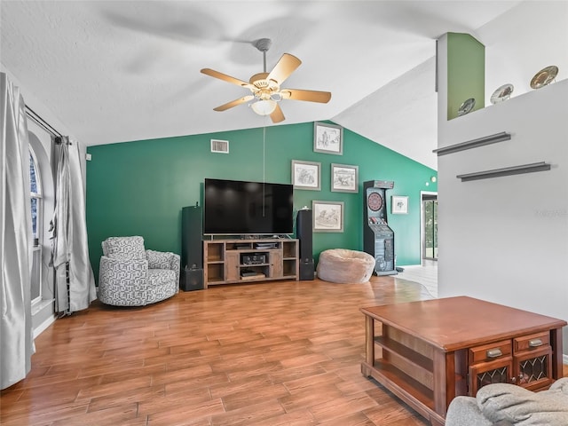 living area with lofted ceiling, ceiling fan, wood finished floors, visible vents, and a healthy amount of sunlight