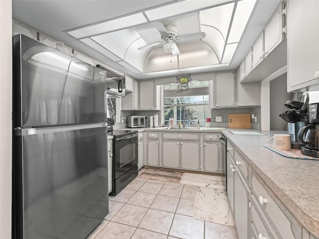 kitchen featuring electric range, a raised ceiling, freestanding refrigerator, light countertops, and backsplash