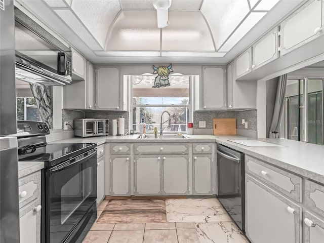 kitchen featuring dishwasher, black electric range, a tray ceiling, and light countertops