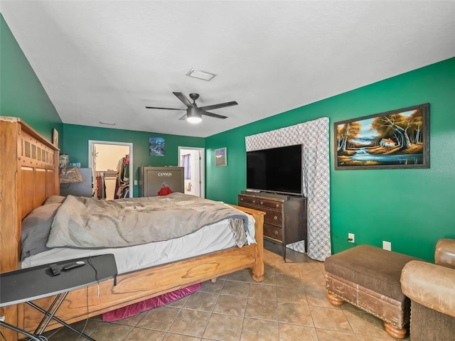 tiled bedroom featuring visible vents, ceiling fan, an accent wall, a spacious closet, and a closet