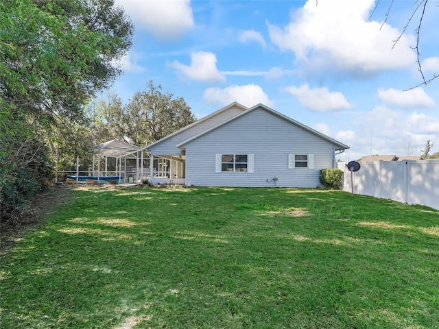 back of house with glass enclosure, a yard, fence, and a pool