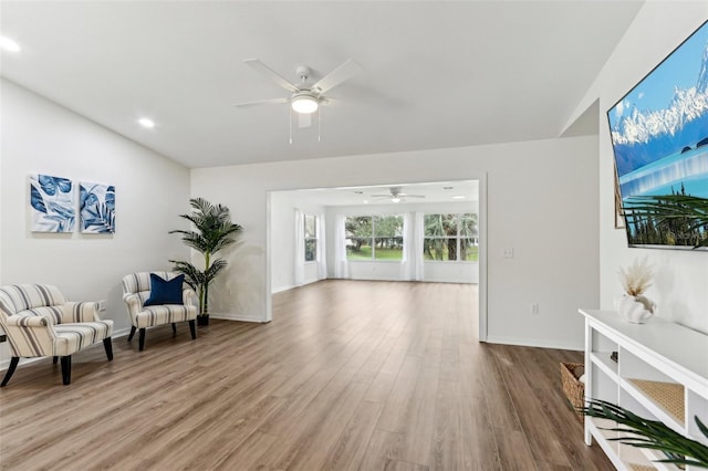 living area featuring a ceiling fan, baseboards, and wood finished floors