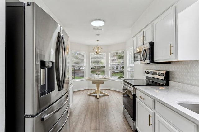 kitchen featuring pendant lighting, visible vents, appliances with stainless steel finishes, white cabinetry, and light wood-type flooring