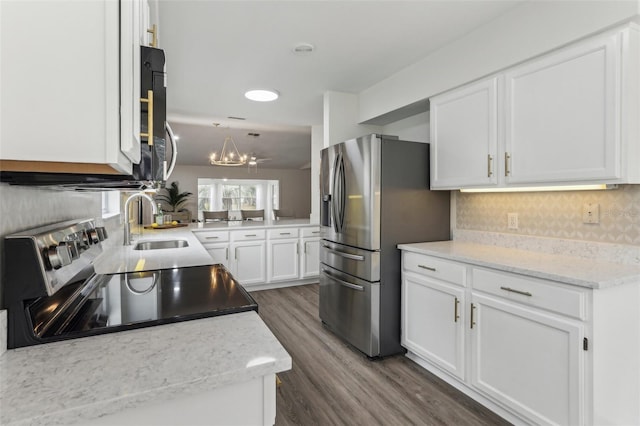 kitchen featuring appliances with stainless steel finishes, dark wood-type flooring, a sink, white cabinetry, and backsplash