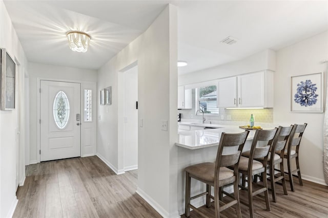 foyer featuring baseboards, visible vents, and light wood finished floors