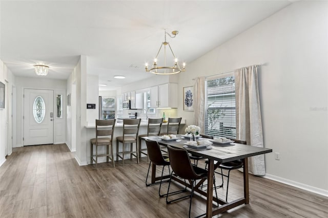 dining room featuring a chandelier, wood finished floors, lofted ceiling, and baseboards