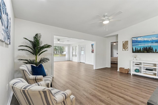 living area with ceiling fan, vaulted ceiling, wood finished floors, and baseboards