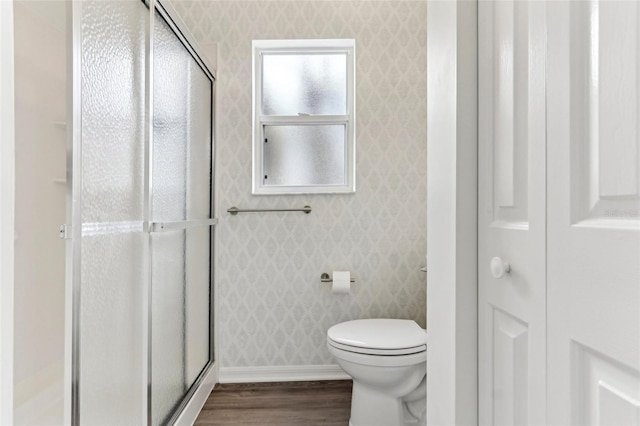 bathroom with wood finished floors, a closet, toilet, and wallpapered walls