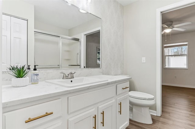 full bath featuring baseboards, toilet, wood finished floors, vanity, and a shower stall