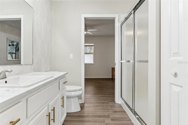 full bathroom with toilet, a stall shower, wood finished floors, and vanity