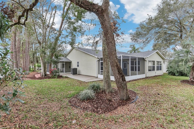 rear view of property featuring cooling unit, a lanai, a patio area, and a lawn