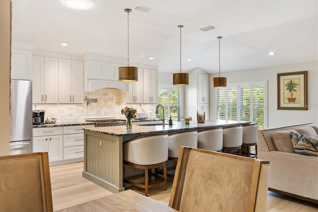 kitchen with stainless steel appliances, a sink, light wood-style flooring, and a breakfast bar area