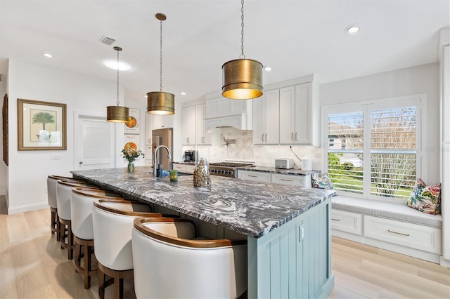 kitchen with tasteful backsplash, light wood-type flooring, a breakfast bar, and stove