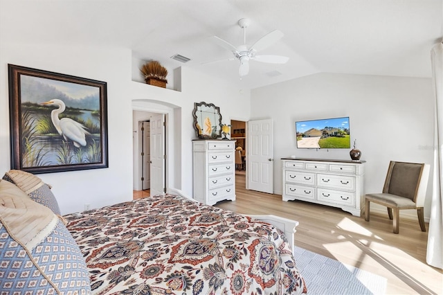 bedroom with arched walkways, light wood finished floors, visible vents, vaulted ceiling, and ceiling fan