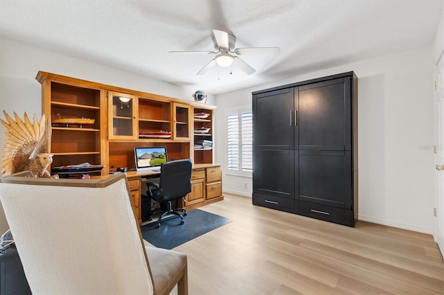 office with light wood-style floors, ceiling fan, a textured ceiling, and baseboards