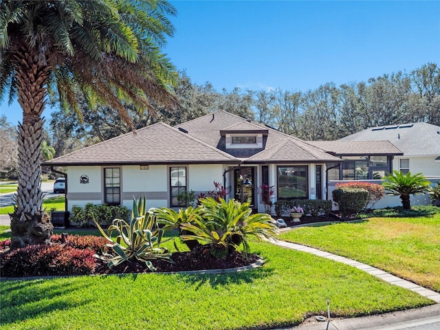 view of front facade with roof with shingles, a front lawn, and stucco siding