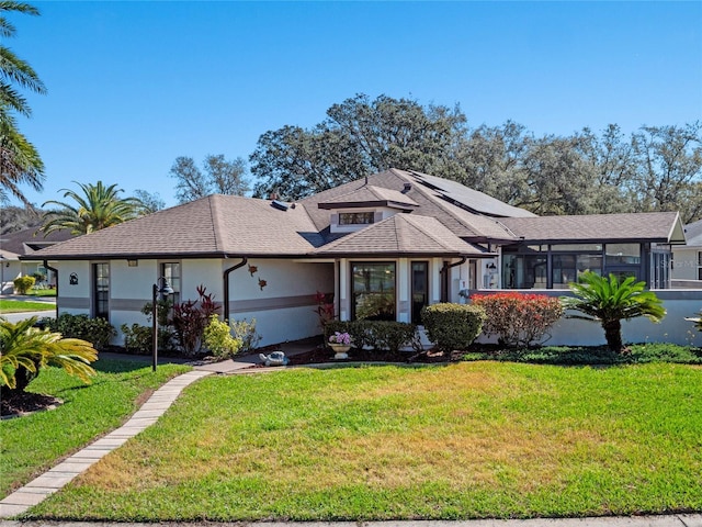 view of front of house featuring a front yard, a sunroom, and stucco siding