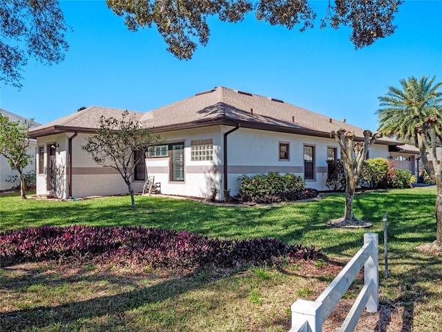 view of home's exterior with a lawn, fence, and stucco siding