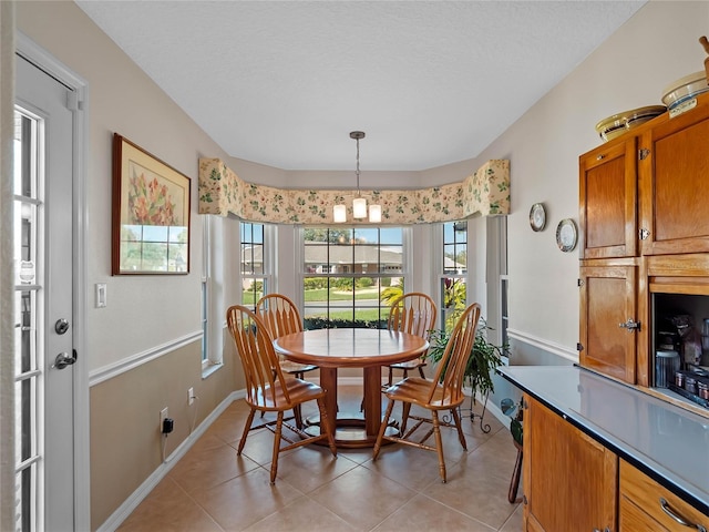 dining space featuring light tile patterned floors, a textured ceiling, baseboards, and a notable chandelier