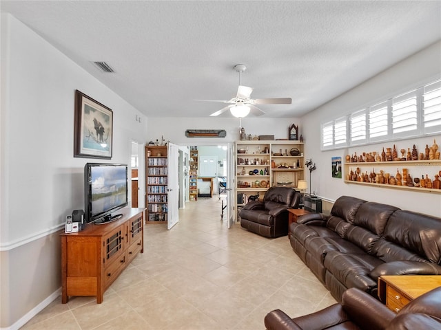 living area featuring a ceiling fan, visible vents, a textured ceiling, and light tile patterned flooring