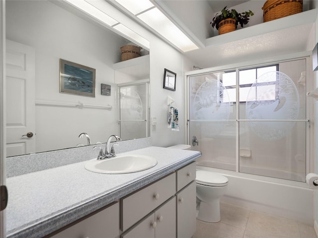 bathroom featuring tile patterned flooring, combined bath / shower with glass door, vanity, and toilet