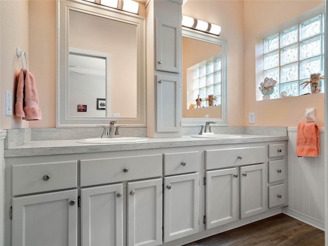 full bath with double vanity, a sink, and wood finished floors