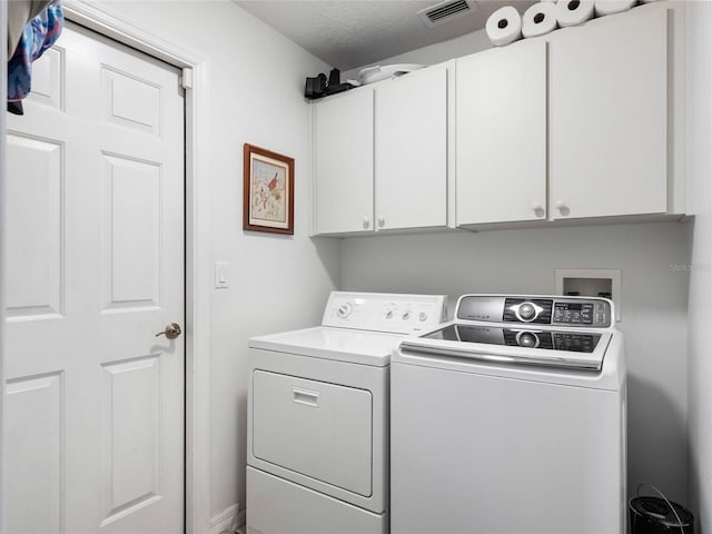 washroom featuring cabinet space, visible vents, a textured ceiling, and independent washer and dryer