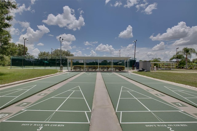 surrounding community featuring shuffleboard, a lawn, and fence