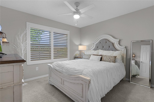 bedroom with a textured ceiling, a ceiling fan, baseboards, and light carpet