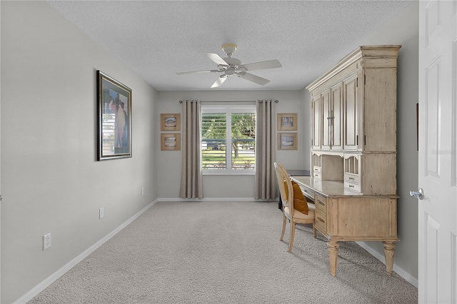 office space featuring a textured ceiling, light carpet, baseboards, and ceiling fan