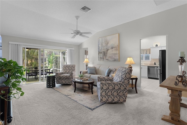 living room featuring light carpet, a textured ceiling, vaulted ceiling, visible vents, and ceiling fan