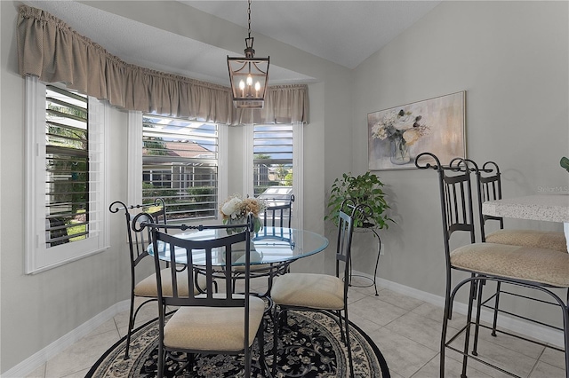 dining area featuring light tile patterned floors, vaulted ceiling, baseboards, and an inviting chandelier