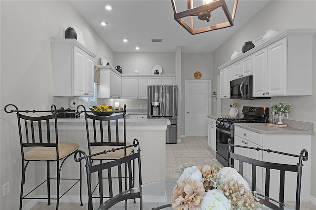 kitchen featuring range with gas cooktop, visible vents, black microwave, a peninsula, and stainless steel fridge