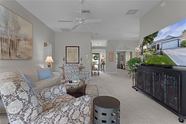 carpeted living area with visible vents, arched walkways, and ceiling fan