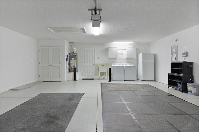 garage with water heater, a garage door opener, washer and clothes dryer, a sink, and freestanding refrigerator